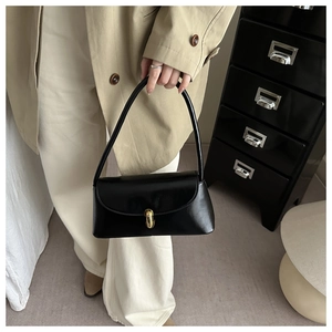 Classic black baguette bag with gold buckle shown on shoulder for a stylish commuter look