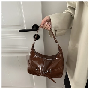 Détail d'un sac à main marron vintage en cuir brillant avec boucle et fermeture éclair