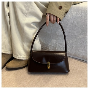 Close-up of a dark brown glossy leather handbag with a golden oval twist lock