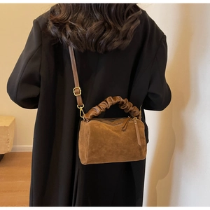 Gros plan d'un sac oreiller en daim marron avec poignée nuage froncée et détails dorés