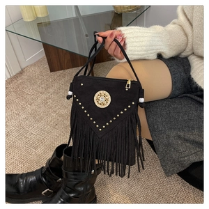 Detail of bohemian black suede handbag with gold rivets, tassels and crystal emblem