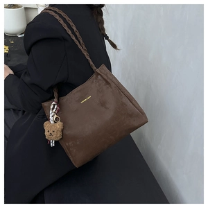 Detail of dark brown suede tote bag with woven straps and cute plush bear charm