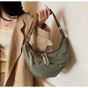 Detail of army green nylon crescent bag with adjustable strap and woven zipper pull