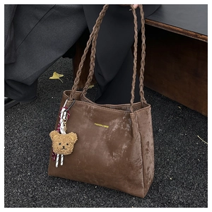 Detail of coffee brown tote bag with woven straps and a plush bear pendant charm
