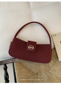 Detailed close-up of retro burgundy underarm bag with gold oval buckle and suede texture