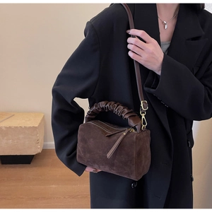 Détail du sac Boston en daim marron foncé avec poignées plissées et finitions dorées
