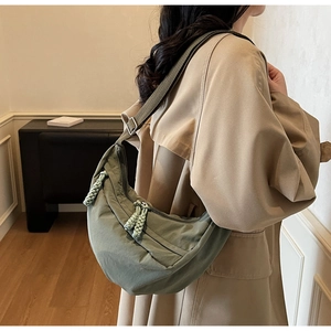 Detailed close-up of a large olive green nylon crescent crossbody bag on a model