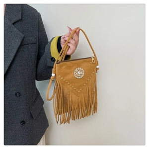 Detail of yellow suede handbag with bohemian fringe, rivets and rhinestone buckle
