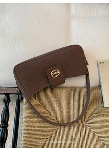 Detailed view of dark brown suede bag with gold horsebit buckle on a chair