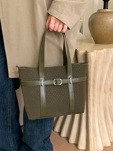 Olive green tote bag with woven texture and silver buckle shown in a lifestyle scene