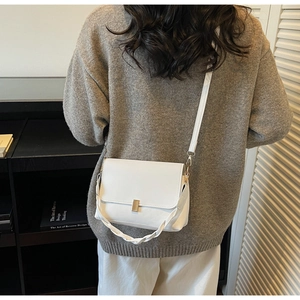 Détail du sac bandoulière blanc avec poignée tressée et boucle métallique