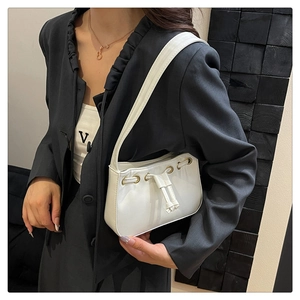 Detail of white leather shoulder bag featuring drawstring design and gold eyelets