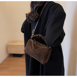 Détail du sac carré en daim marron foncé avec poignées plissées et fermetures dorées