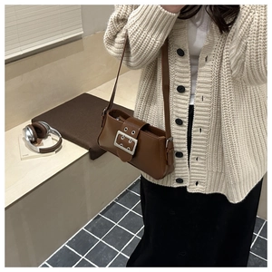 Détail du sac à bandoulière en cuir marron foncé avec boucle de ceinture argentée