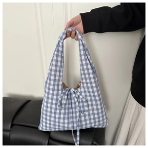 Detail of blue and white checkered canvas handbag featuring a decorative knot bow design