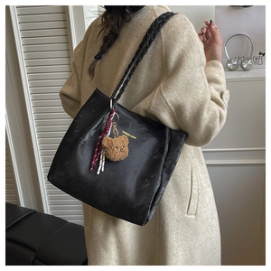 Detail showing black tote bag texture with woven straps and cute brown bear pendant