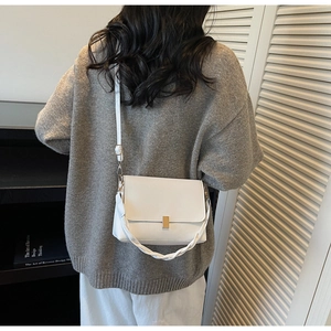 Détail du sac bandoulière blanc avec fermoir doré et poignée tressée élégante
