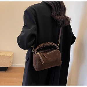 Détail du sac à main en daim marron foncé avec poignée plissée et fermetures dorées