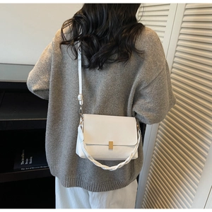 Sac à bandoulière en cuir blanc avec fermoir doré et bandoulière tressée porté