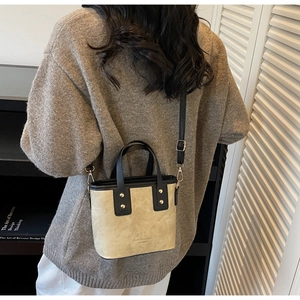 Detail of beige and black bucket bag with gold hardware and logo on textured leather
