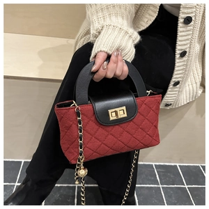 Détail du sac seau bordeaux matelassé avec breloque boule dorée et bandoulière chaîne
