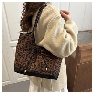 Leopard-Tragetasche mit schwarzen Lederdetails und Schleife am Modell gezeigt