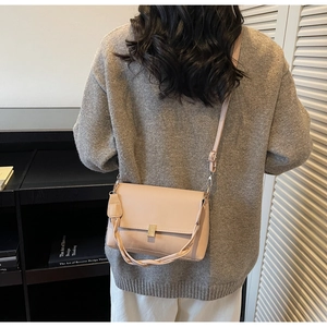 Sac bandoulière rose clair avec poignée tressée et fermoir doré porté par le modèle