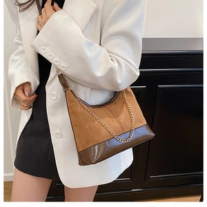 Borsa a spalla in pelle scamosciata marrone con catena dorata indossata su blazer bianco