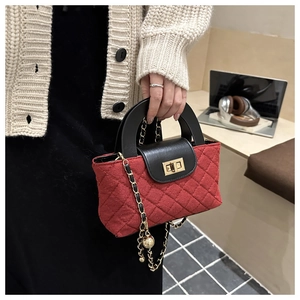 Détail du sac seau en tweed matelassé rouge avec rabat en cuir noir et fermoir doré