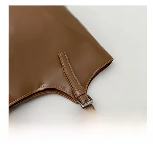 Detailed macro of silver buckle and leather strap stitching on brown shoulder bag