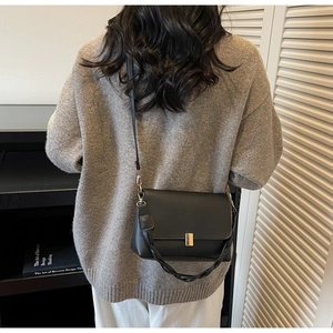 Détail du sac bandoulière en cuir noir avec bandoulière torsadée et fermoir doré chic