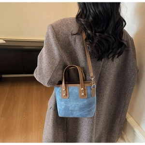Mini blue denim tote bag with brown leather straps shown on a model's back