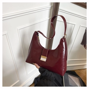 Detail of burgundy glossy leather bucket bag with elegant golden metallic buckle