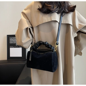 Détail d'un sac oreiller en daim noir avec poignée froncée et bandoulière réglable