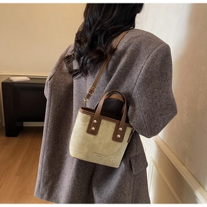 Detail view of light green bucket bag with brown leather straps and gold stud accents