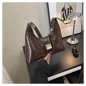 Detail of dark brown glossy patent leather bucket bag with golden buckle and chain strap