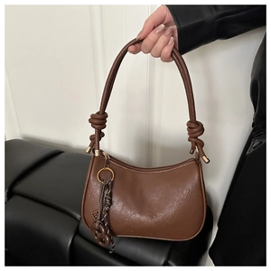 Détail d'un sac à bandoulière demi-lune en cuir PU marron avec bandoulière nouée et pendentif
