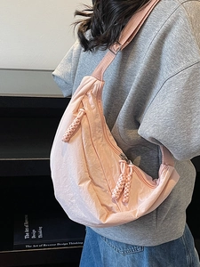 Pink crescent nylon crossbody bag with adjustable strap and textured finish for travel