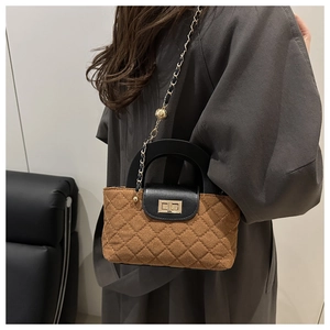 Détail du sac seau matelassé vintage avec fermoir doré et bandoulière en chaîne cuir