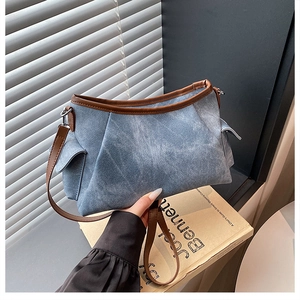 Detail of light blue denim shoulder bag with brown leather trim and pleated design