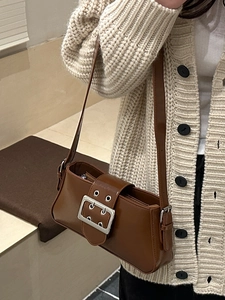 Brown minimalist baguette bag with large silver buckle shown on shoulder of a model