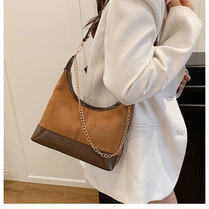 Dettaglio borsa hobo patchwork marrone con catena dorata indossata da una modella