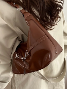 Sac bandoulière marron brillant porté avec un trench pour un look mode épuré