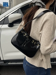 Minimalist black patent leather square shoulder bag with gold metal rings and drawstrings