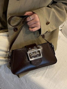 Dark brown shiny leather underarm baguette bag with a large silver buckle decoration