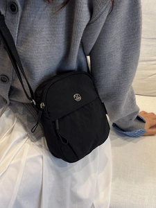 Schwarze Umhängetasche aus Nylon mit Doppelreißverschluss und M-Logo in Alltagsszene