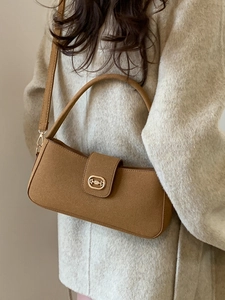 Brown matte suede shoulder bag with gold horsebit buckle on a beige coat model