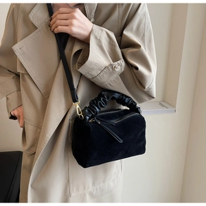 Détail du sac polochon en daim noir avec poignée plissée nuage et fermoirs dorés chic