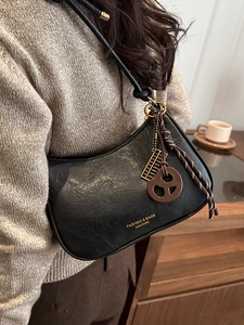 Sac hobo rétro en cuir noir avec pendentif abaque doré et bandoulière texturée élégante