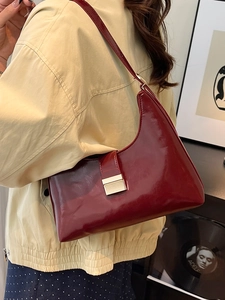 Deep red oily leather shoulder bag with gold clasp shown on model in a retro setting
